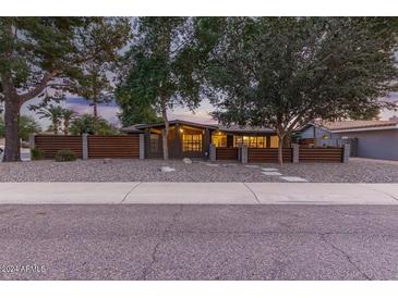 Mid-century modern home with wood fence, gravel landscaping and walkway at 8325 E Crestwood Way, Scottsdale, AZ 85250
