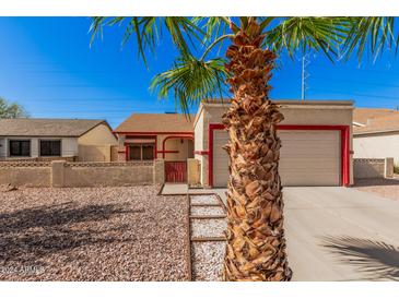 House exterior with a beige stucco finish, red accents, and a two-car garage at 10014 N 66Th Ln, Glendale, AZ 85302