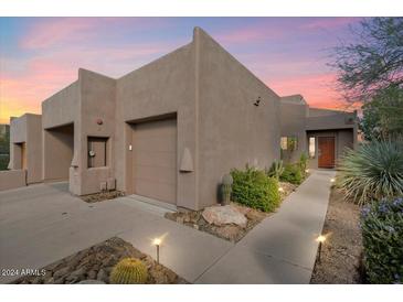 Desert landscape home with stucco exterior, attached garage, and lighted walkway at 9220 E Whitethorn Cir, Scottsdale, AZ 85266