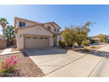 Two-story house with a tan facade, two-car garage, and landscaping at 665 W Gabrilla Ct, Casa Grande, AZ 85122