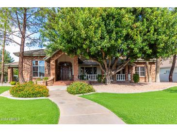 Brick house with a large tree, walkway, and manicured lawn at 2166 E Caroline Ln, Tempe, AZ 85284