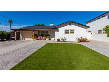 White single story home with artificial turf lawn and a wood fence at 4002 E Clarendon Ave, Phoenix, AZ 85018