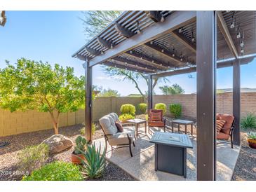 Covered patio with seating area, fire pit, and desert landscaping at 31498 N 129Th Dr, Peoria, AZ 85383