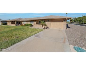 Tan one-story home with attached garage and manicured lawn at 9902 W Sandstone Dr, Sun City, AZ 85351