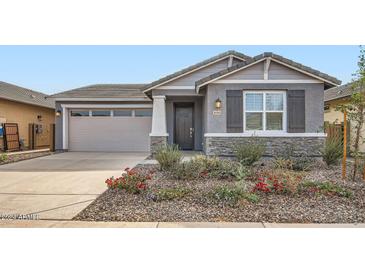 Single-story home with gray siding, stone accents, and landscaping at 36545 W Leonessa Ave, Maricopa, AZ 85138