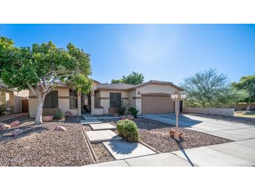 Tan house exterior with a two-car garage and landscaping at 7585 W Tumblewood Dr, Peoria, AZ 85382