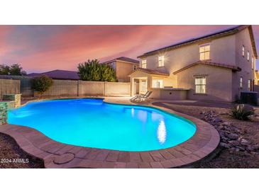 Inviting kidney-shaped pool with surrounding patio and landscape lighting at 2660 S 172Nd Dr, Goodyear, AZ 85338