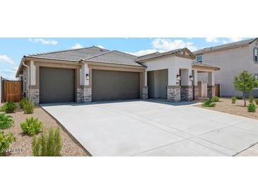 Modern three-car garage home with stone accents and landscaping at 9911 S Caballo Dr, Apache Junction, AZ 85120