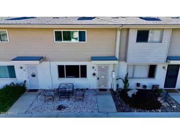 Front view of a tan colored two-story home with small front yard and seating area at 8221 E Garfield St # L09, Scottsdale, AZ 85257