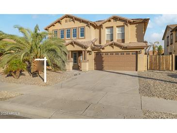 Two-story house with tan exterior, large garage, and palm trees in front at 16800 W Mesquite Dr, Goodyear, AZ 85338