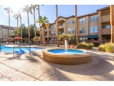 Community pool and fountain area with palm trees and surrounding landscaping at 14950 W Mountain View Blvd # 4205, Surprise, AZ 85374