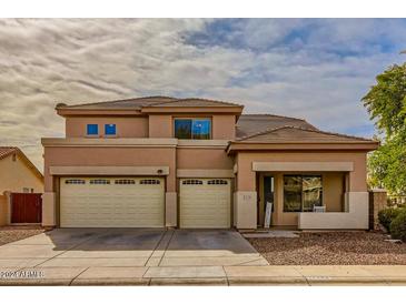 Two-story house with tan exterior, two-car garage, and landscaping at 14449 W Evans Dr, Surprise, AZ 85379