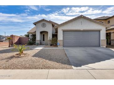 Single-story home with gray garage door and landscaped front yard at 15547 W Magnolia St, Goodyear, AZ 85338