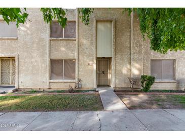 Tan two-story condo building with a walkway and landscaping at 8027 N 32Nd Ave, Phoenix, AZ 85051