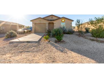 Tan house with a garage and landscaped yard at 32010 N Redding St, Wittmann, AZ 85361