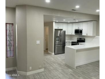 Modern kitchen with white cabinets, stainless steel appliances, and a large island at 8351 W Taro Ln, Peoria, AZ 85382