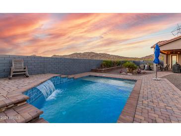 Inviting backyard oasis featuring a sparkling pool and waterfall, perfect for relaxation at 18668 W Chuckwalla Canyon Rd, Goodyear, AZ 85338