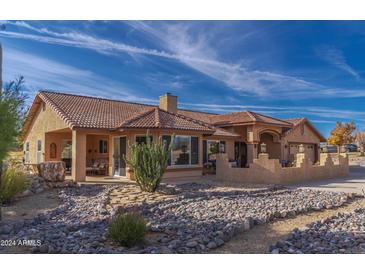 One-story stucco home with tile roof, landscaped yard, and attached garage at 2125 W Bromm Ln, Wickenburg, AZ 85390