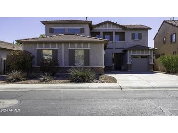 Two-story house with gray siding, a three-car garage, and landscaping at 297 W Seaside Dr, Casa Grande, AZ 85122