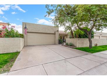 Tan stucco house with a two-car garage and landscaped yard at 7941 E Medlock Dr, Scottsdale, AZ 85250