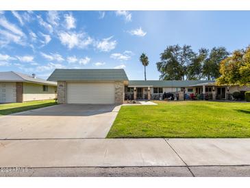 Ranch-style home with a large grassy yard and attached garage at 9913 W Pleasant Valley Rd, Sun City, AZ 85351