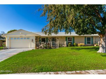 Ranch style home with a spacious lawn and attached garage at 10213 W Kingswood Cir, Sun City, AZ 85351