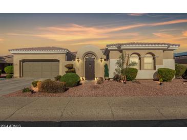 Tan two-story house with arched entryway and landscaped yard at 12844 W El Sueno Dr, Sun City West, AZ 85375