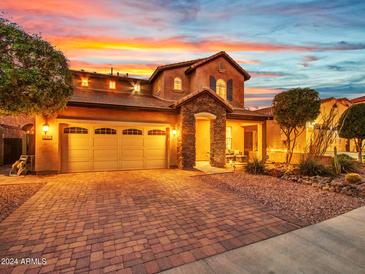 Two-story house with stone accents and a three-car garage, well lit at dusk at 32388 N 129Th Dr, Peoria, AZ 85383