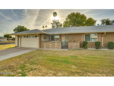 Well-maintained ranch home with a spacious lawn and attached garage at 10401 W Desert Forest Cir, Sun City, AZ 85351