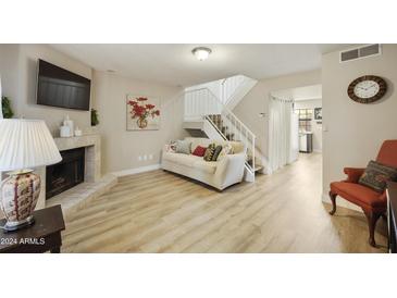 Open living room with fireplace, hardwood floors, and stairs to the upper level at 4901 E Kelton Ln # 1006, Scottsdale, AZ 85254