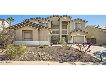 Two-story house with a neutral color scheme, landscaping, and a three-car garage at 6027 N 132Nd Dr, Litchfield Park, AZ 85340