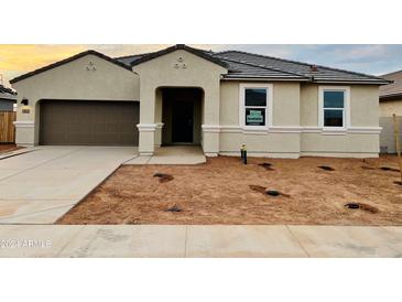 Tan one-story house with brown garage door and landscaping to be installed at 12391 E Bahia Ct, Florence, AZ 85132