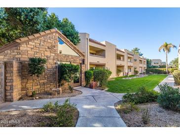 Exterior view of condo building with stone accents and grassy courtyard at 2228 N 52Nd St # 240, Phoenix, AZ 85008