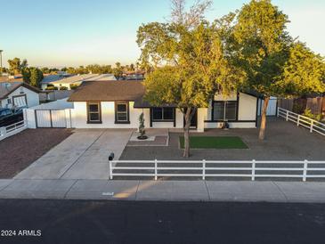 Updated single-level home with front yard landscaping, driveway, and white fence at 7316 W Carol Ave, Peoria, AZ 85345