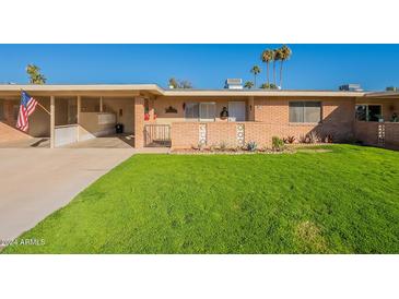Brick ranch home with a grassy yard and palm trees at 10412 W Audrey Dr, Sun City, AZ 85351