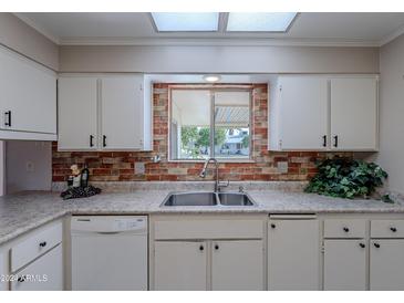 Kitchen with white cabinets, double sink, and a view to the backyard at 10610 W Saratoga Cir, Sun City, AZ 85351