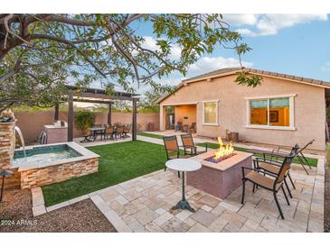 Landscaped backyard oasis with pergola, fire pit, and water feature at 4235 W Palace Station Rd, New River, AZ 85087