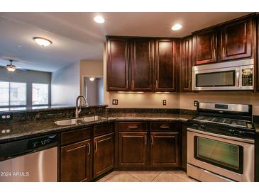 Modern kitchen with dark wood cabinets, granite countertops, and stainless steel appliances at 5350 E Deer Valley Dr # 2268, Phoenix, AZ 85054