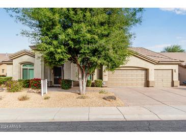 Tan two-story house with a three-car garage and landscaped yard at 6442 E Winchcomb Dr, Scottsdale, AZ 85254