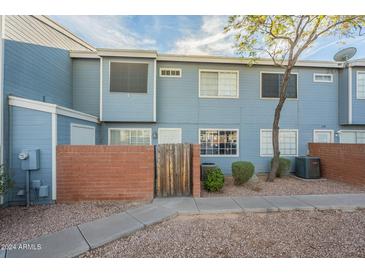 Front view of a light-blue townhome with a brick wall and gated entryway at 2301 E University Dr # 339, Mesa, AZ 85213