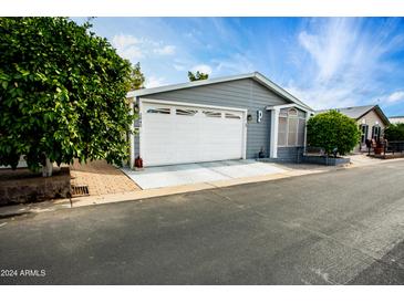 Gray exterior of manufactured home with white garage door and landscaped yard at 650 N Hawes Rd # 2840, Mesa, AZ 85207