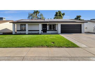 House exterior featuring a well-manicured lawn and solar panels at 9437 N 63Rd Dr, Glendale, AZ 85302