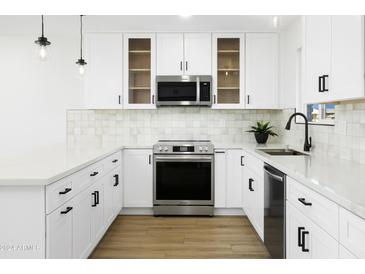 Modern white kitchen with stainless steel appliances and a large island at 10035 N 103Rd Dr, Sun City, AZ 85351