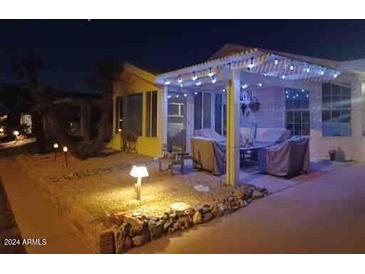 Inviting front yard with covered patio, string lights, and landscaping at night at 215 N Power Rd # 404, Mesa, AZ 85205