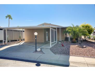 Tan single-wide manufactured home with carport and landscaped yard at 2233 E Behrend Dr # 84, Phoenix, AZ 85024