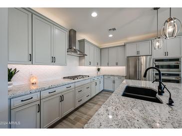 Modern kitchen with gray cabinets, granite countertops, and stainless steel appliances at 16071 W Sand Hills Rd, Surprise, AZ 85387