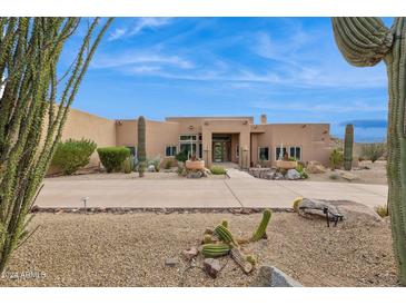 Desert landscape surrounds this single-story home with stucco exterior and large windows at 24200 N Alma School Rd # 29, Scottsdale, AZ 85255