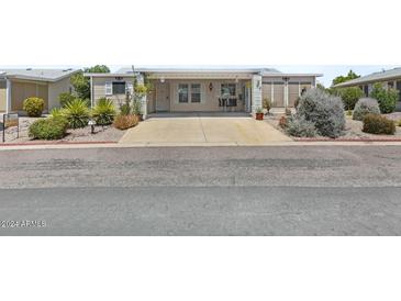 Beige manufactured home with covered porch, landscaping, and driveway at 215 N Power Rd # 361, Mesa, AZ 85205