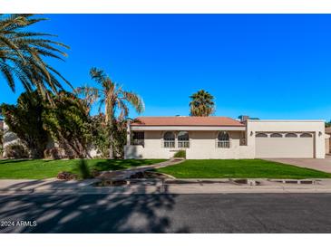 Single story home with arched windows, landscaped lawn, and a two-car garage at 1622 E Hope St, Mesa, AZ 85203