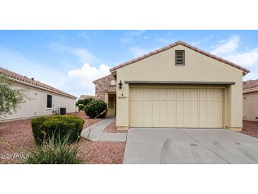 Tan house with stone accents, two-car garage, and landscaped yard at 22409 N Los Gatos Dr, Sun City West, AZ 85375
